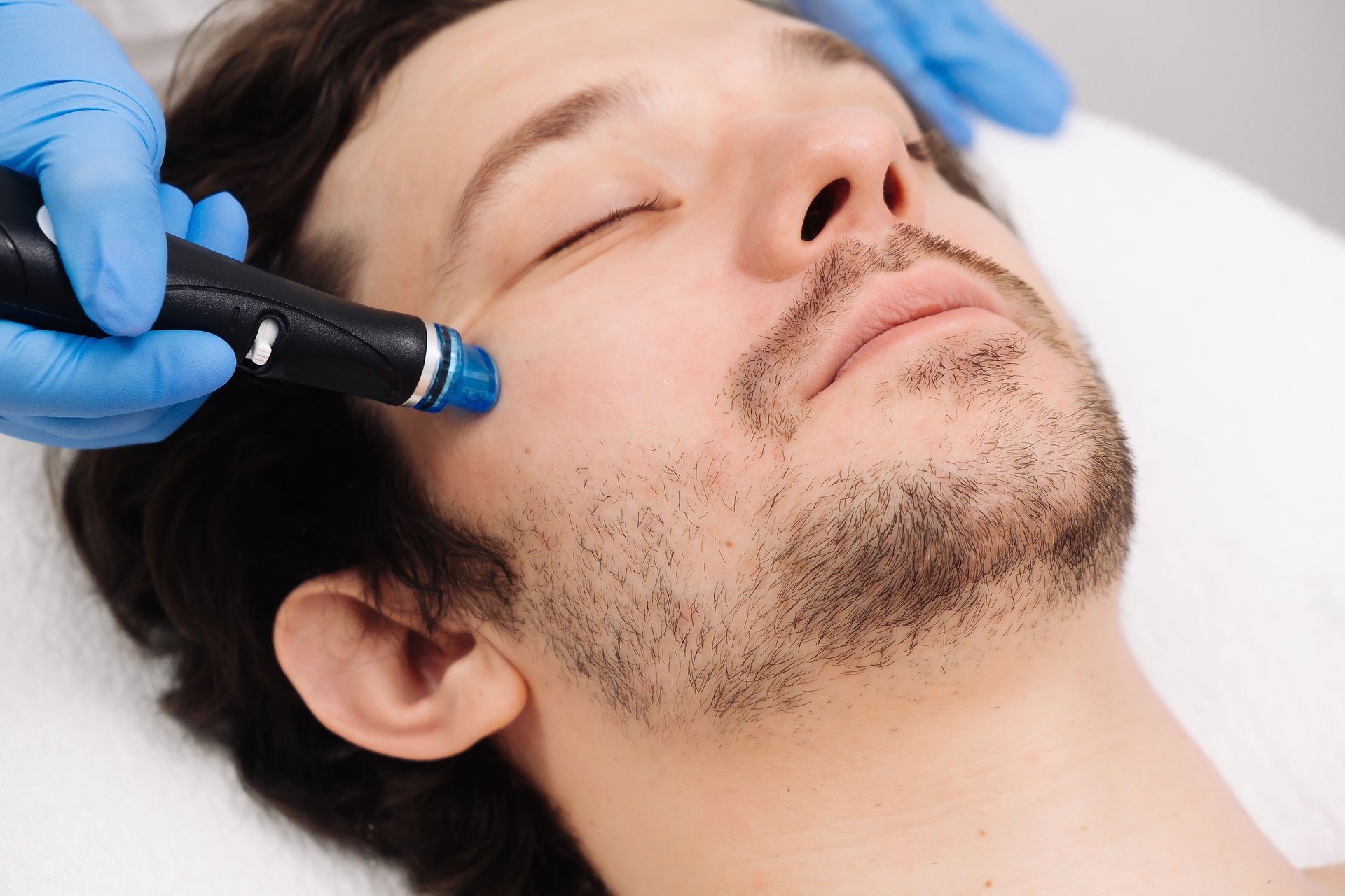 A man undergoes a hydrofacial treatment at a beauty clinic. This advanced procedure rejuvenates and revitalizes the skin, ideal for showcasing premium skincare services in your advertising.